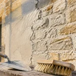Enduit pierre vue : mortier de chaux sur façade en pierre, truelle et brosse